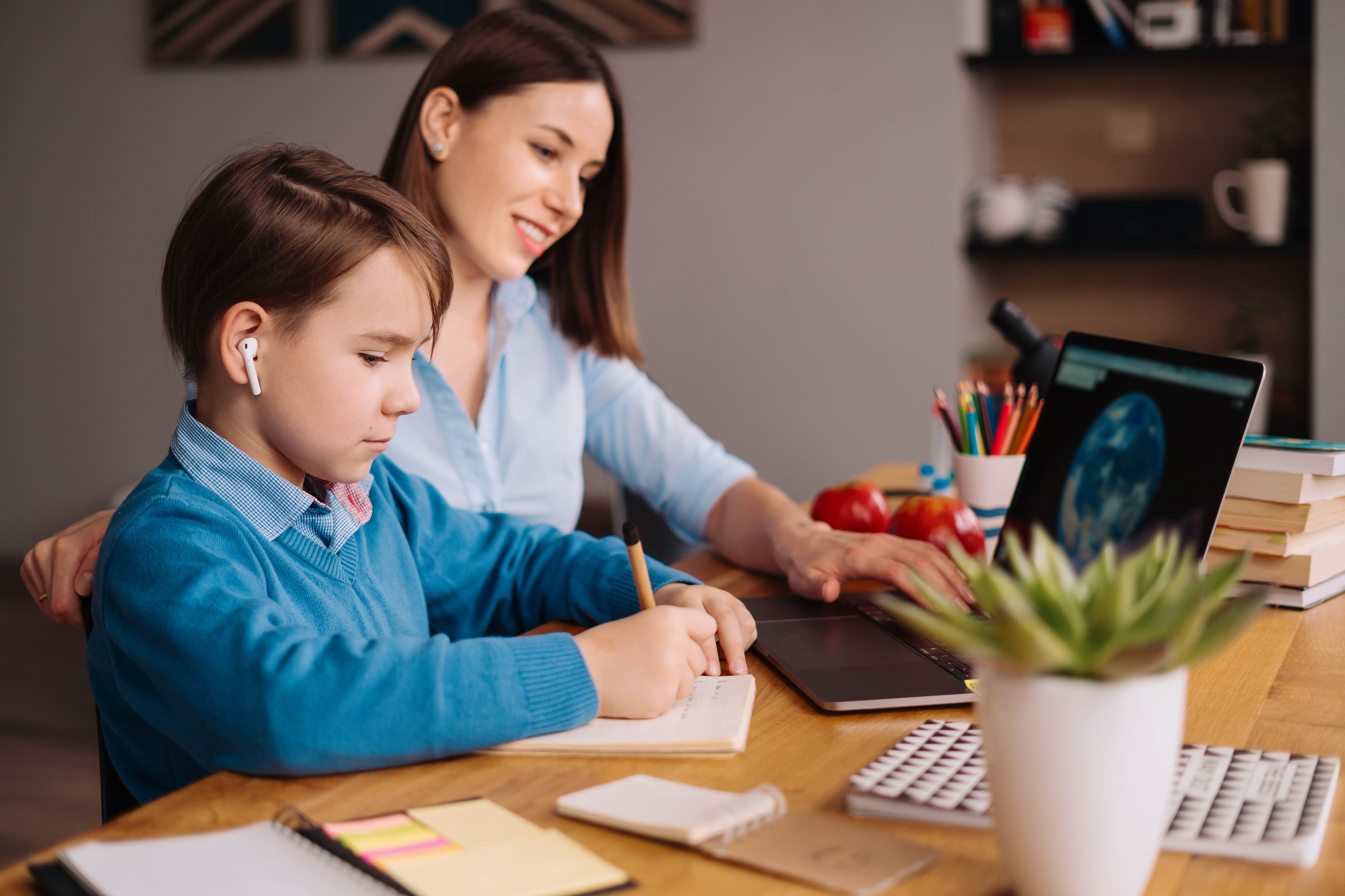 Mother helping son with homeschool lessons on laptop